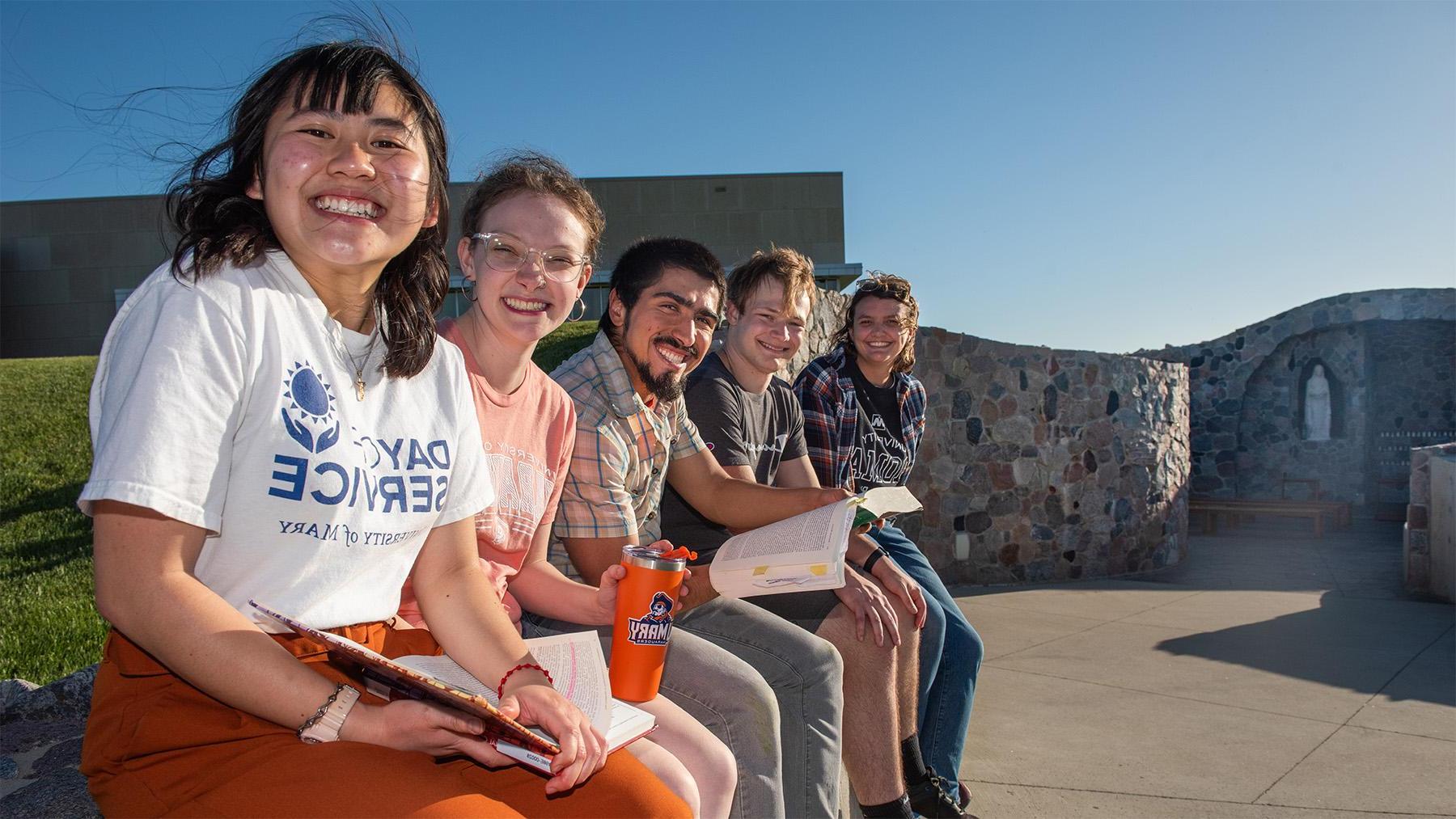 Students sitting by the University of Mary Marian Grove.